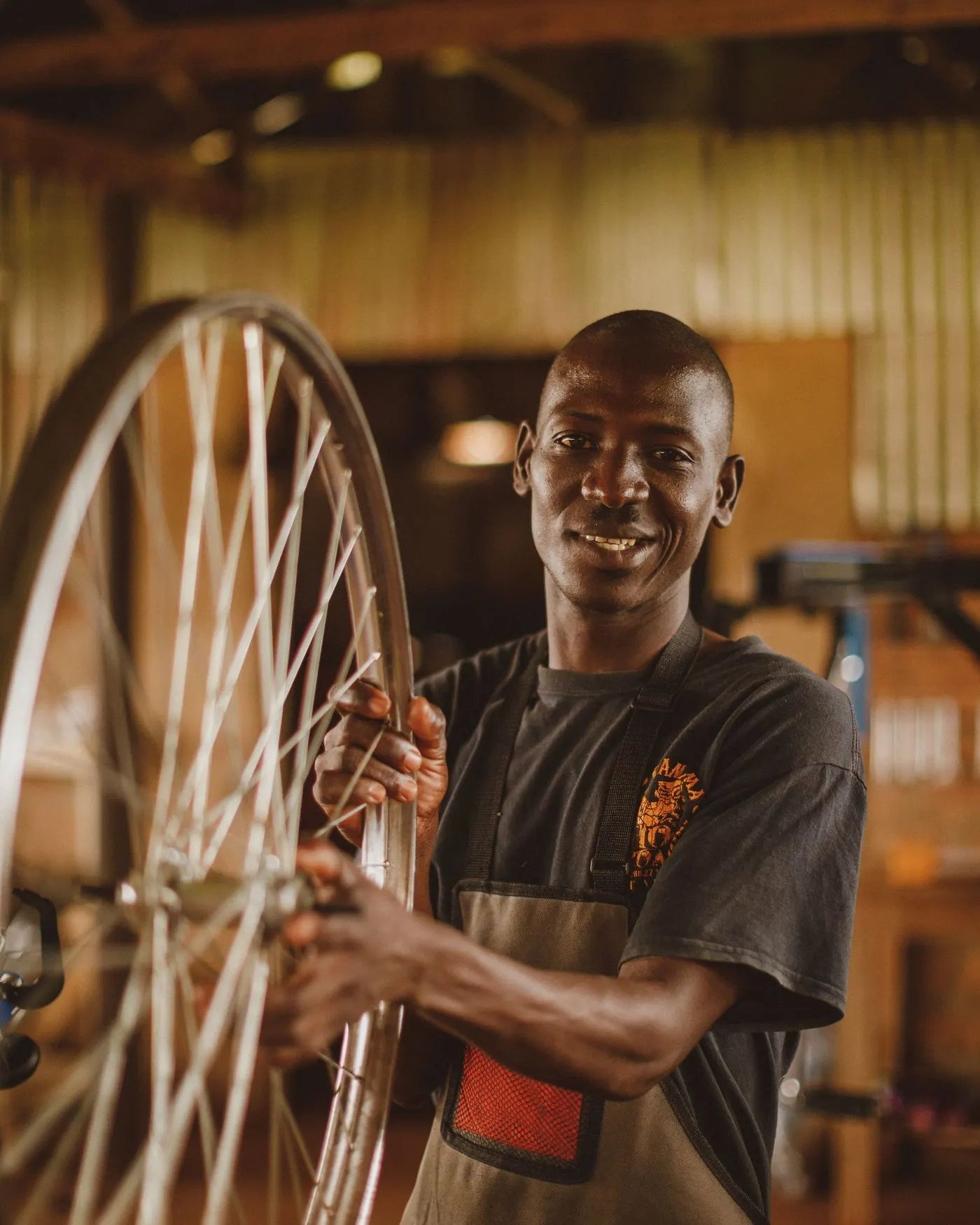 Réparateur souriant tenant une roue de vélo dans son atelier